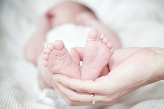 pieds de bébé dans la main de sa maman